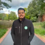 Valor Property Inspections team member in a black fleece jacket with company logo, standing on a path