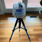 Breeze ET air sampling system on a tripod, positioned on a hardwood floor near a glass door