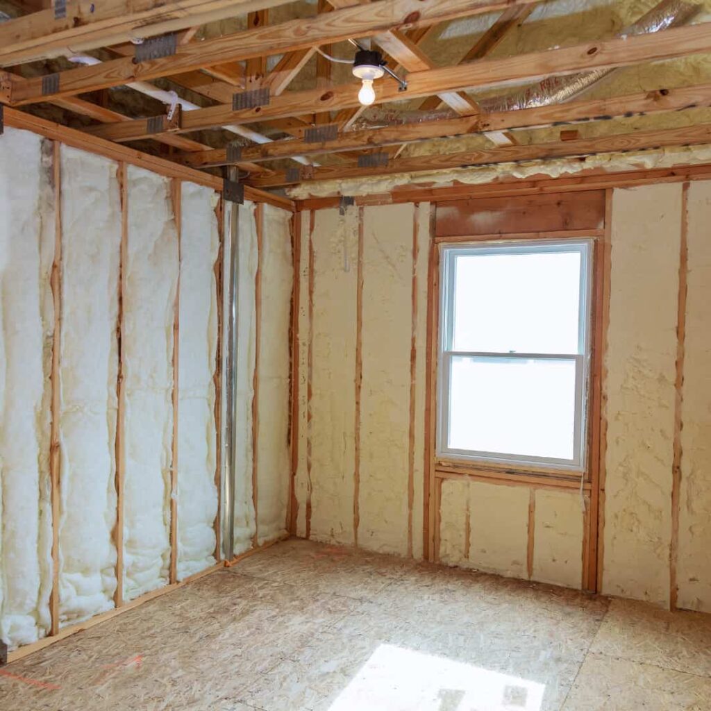 Interior room of a new house with exposed wooden ceiling joists and walls partially insulated with spray foam