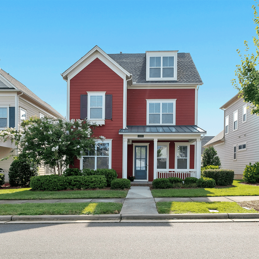 Front exterior of a newly built red two-story house with white trim and a small front porch