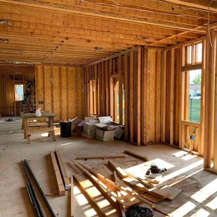 Interior of a house under construction with exposed wooden framing and rough-in electrical wiring